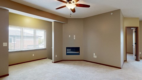 an living room with an electric fireplace, a ceiling fan, and large bay window above the stairs