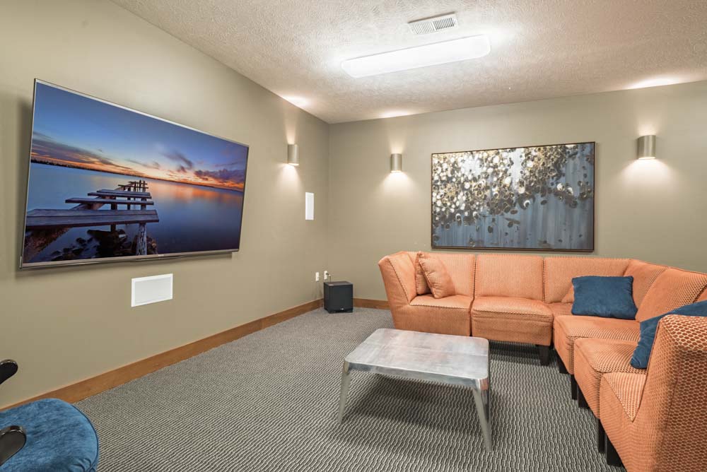 Theater room with large TV and couches at Villas of Omaha townhome apartments in northwest Omaha NE 68116