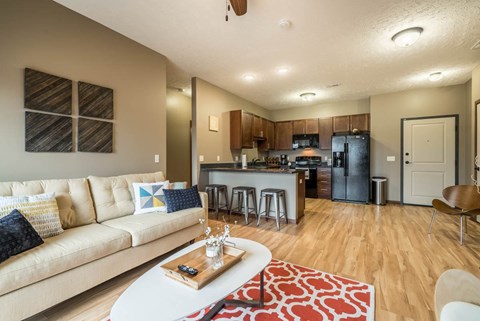 A modern living room with a kitchen in the background.