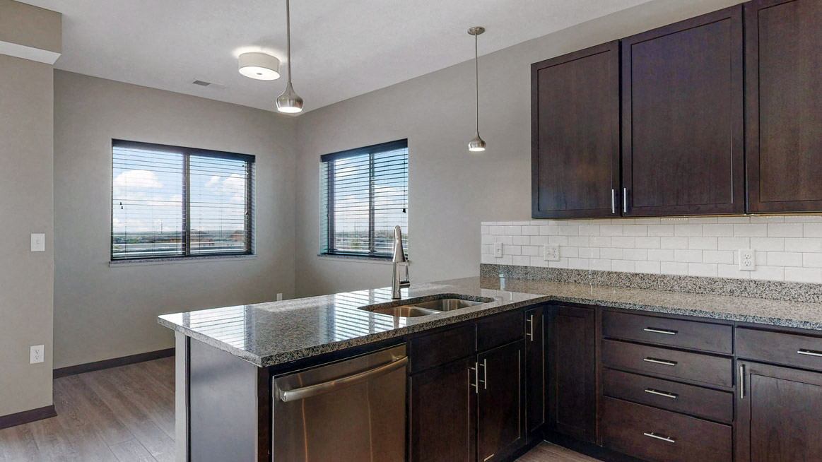 This 2 bedroom Snowdrop with den floor plan at WH Flats features a tile backsplash (available in some homes), stainless steel appliances, granite countertops and large peninsula.