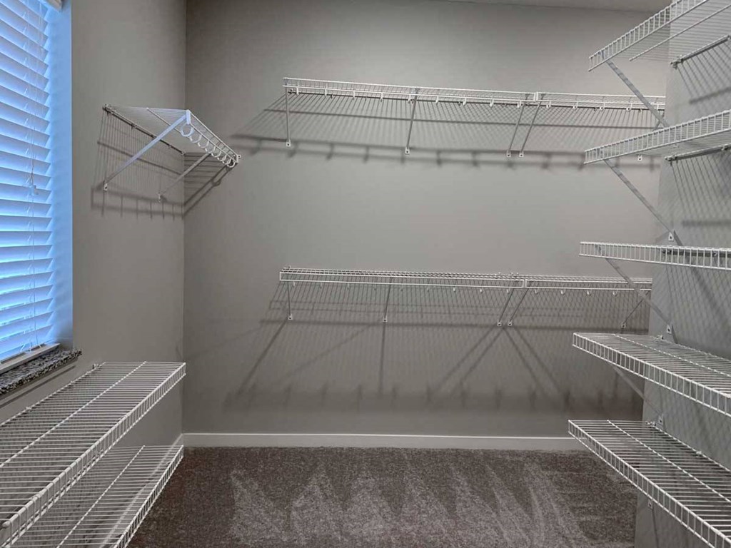 the walk in closet of a home with empty shelves