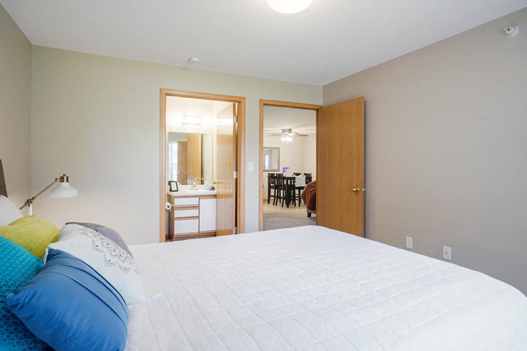 Furnished bedroom with a bed and a door to a bathroom and living area