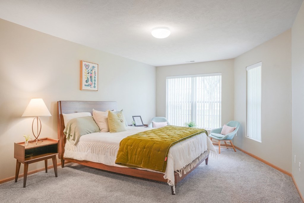 Furnished bedroom with a bed and chairs and a window