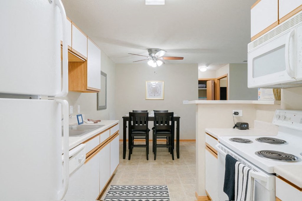 a kitchen with white appliances and a dining room table with chairs in the back