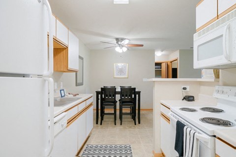 a kitchen with white appliances and a dining room table with chairs