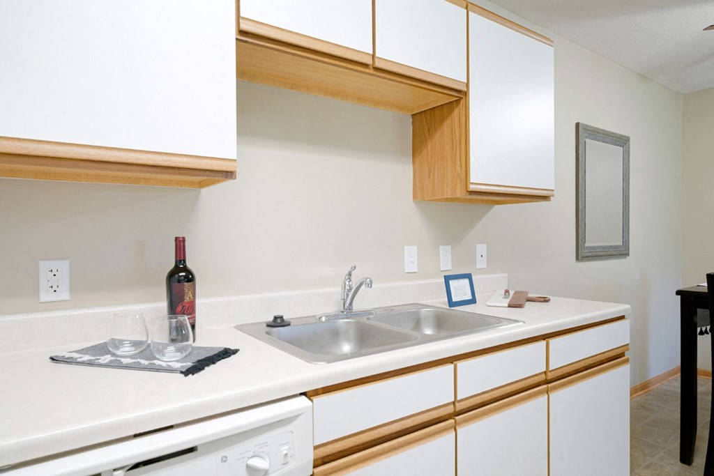a kitchen with a sink and a bottle of wine on the counter