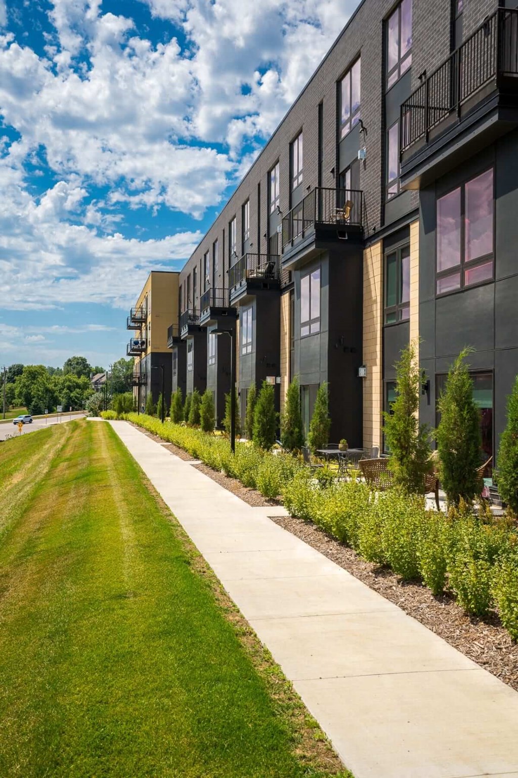 Sidewalk along the Aspire apartment building with grass on the left and the building on the right of the sidewalk