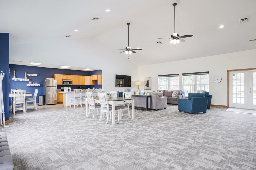 Wide view of the clubhouse at Williamsburg Park with dining table, TV lounge, and community kitchen in the back