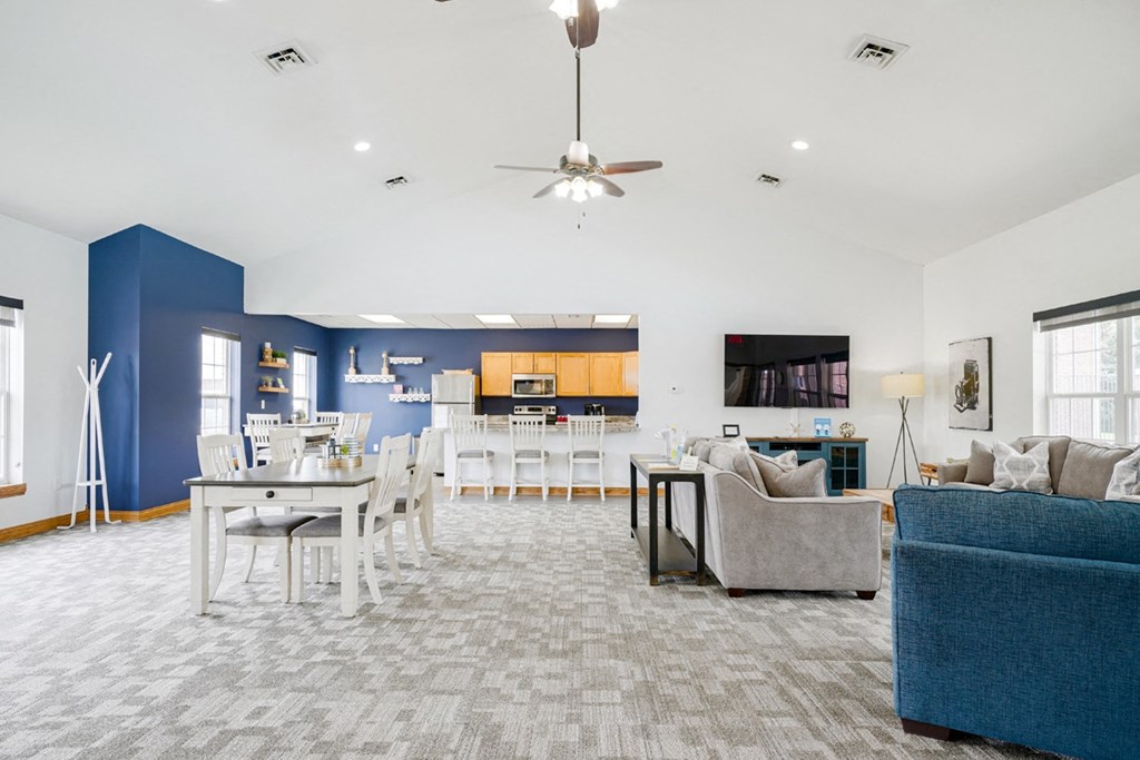Community clubhouse with couches and a dining room with a table and chairs with the kitchen in the back