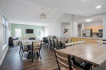 several tables and chairs next to a kitchen and a tv lounge space in the clubhouse