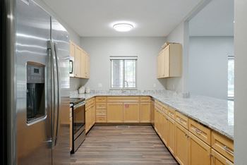 a kitchen with wooden cabinets and granite counter tops in the clubhouse