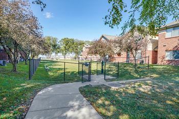 a fenced in dog park next to a sidewalk