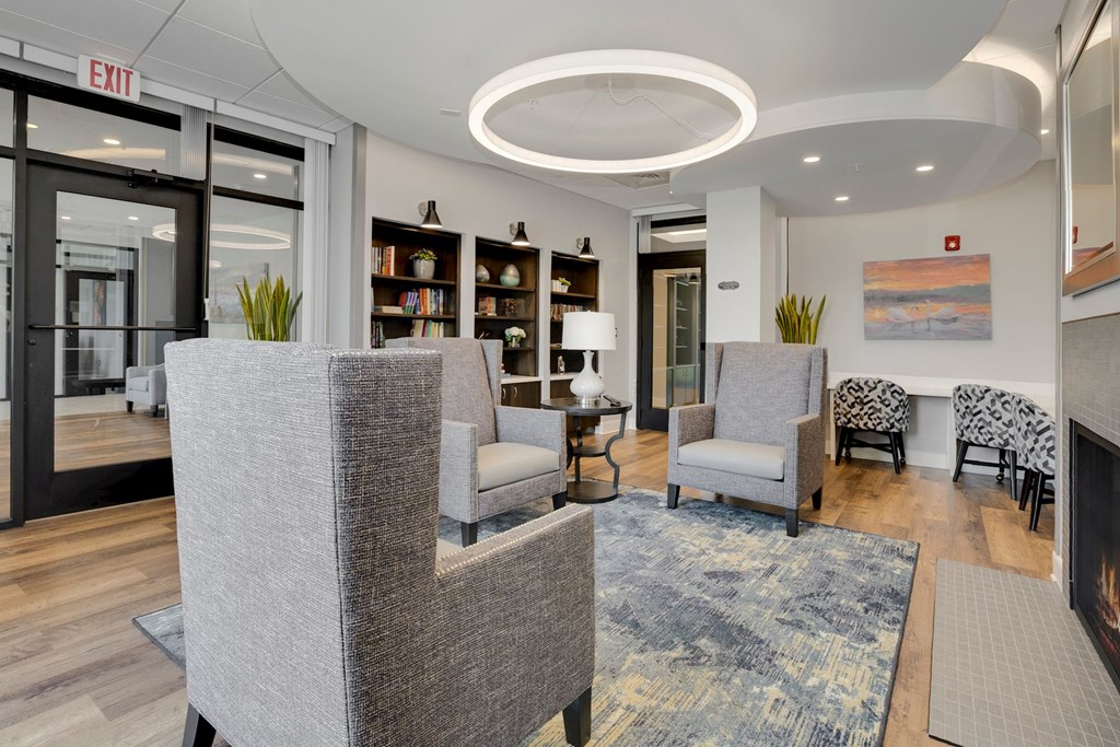 a resident clubhouse with gray chairs and a blue rug