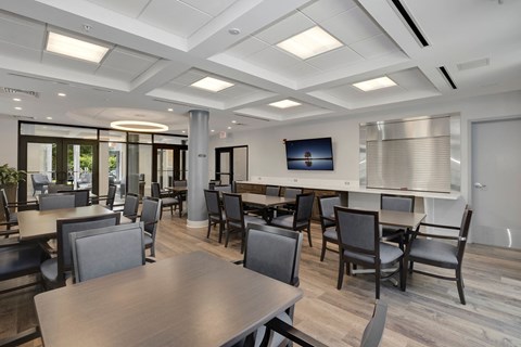 a common room with tables and chairs and a television on the wall