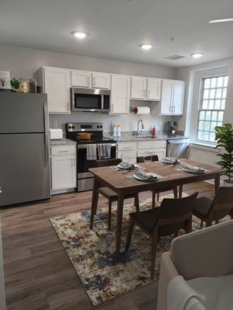 a kitchen with white cabinets and a wooden table in Sandy Spring Village