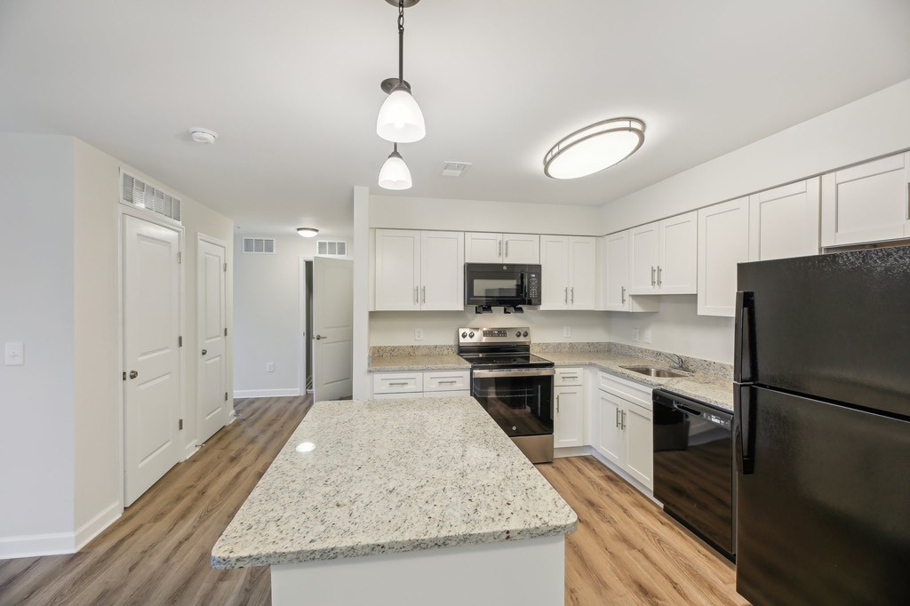A kitchen with a granite countertop and a black refrigerator.