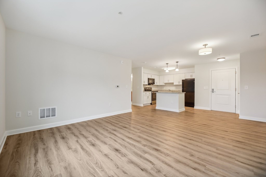 A large empty room with wooden floors and white walls.
