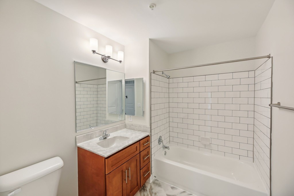 A white bathroom with a sink, mirror, and bathtub.