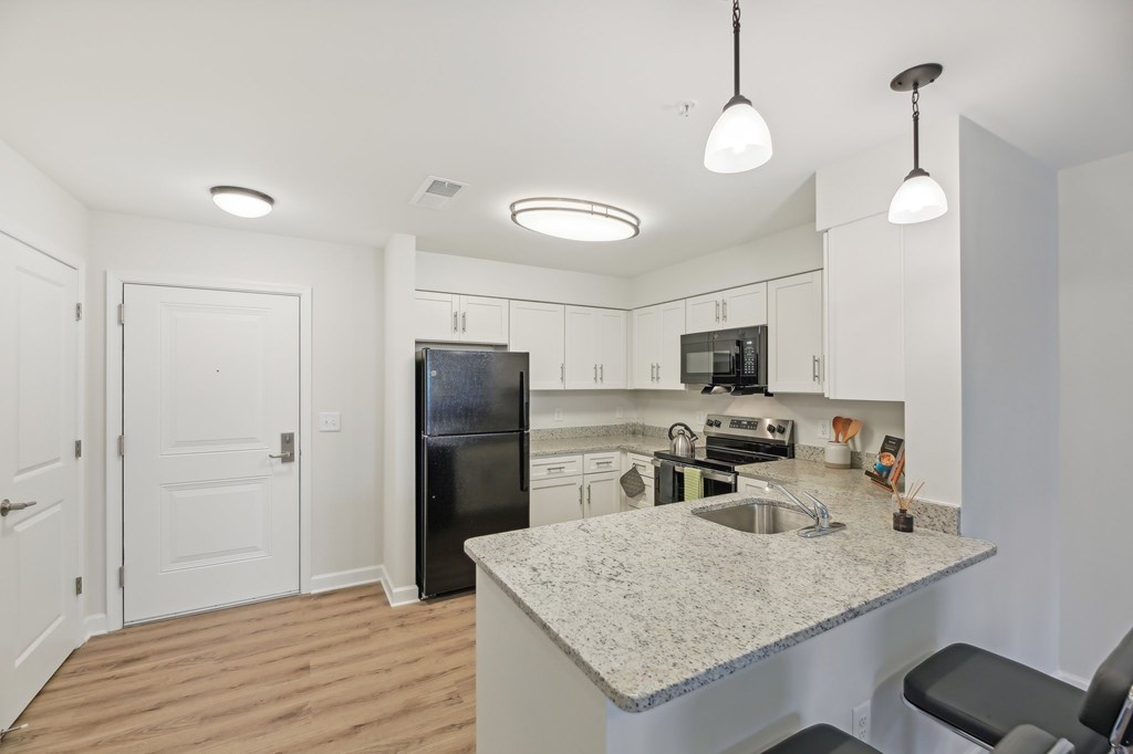 A kitchen with a granite countertop and a black refrigerator.