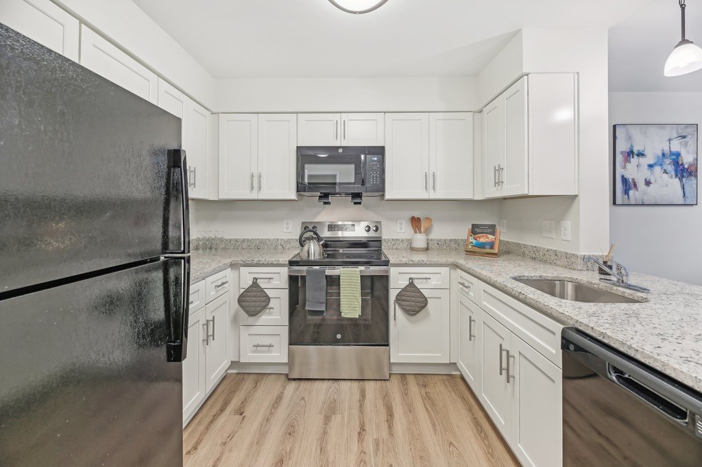 A kitchen with a black refrigerator and white cabinets.