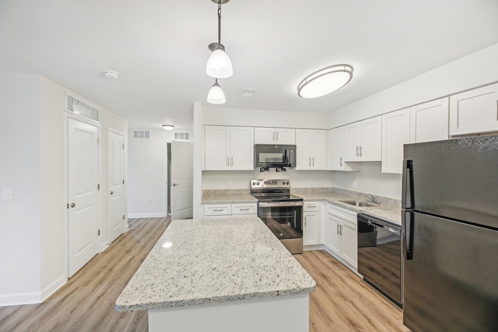 A modern kitchen with a granite countertop and stainless steel appliances.