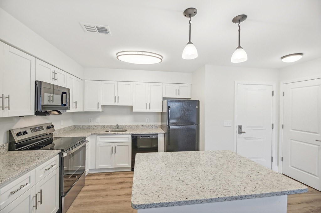 A kitchen with white cabinets and a granite countertop.