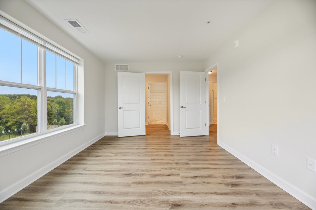 A room with white walls and wooden floors with two white doors.
