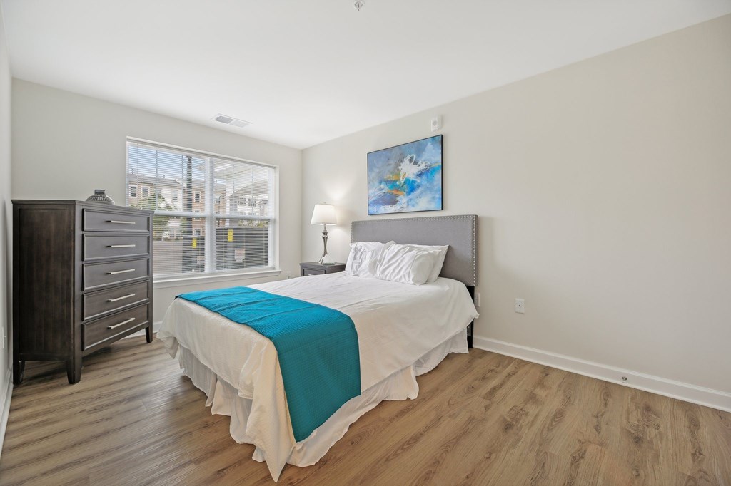 A bedroom with a bed, nightstand, and dresser.