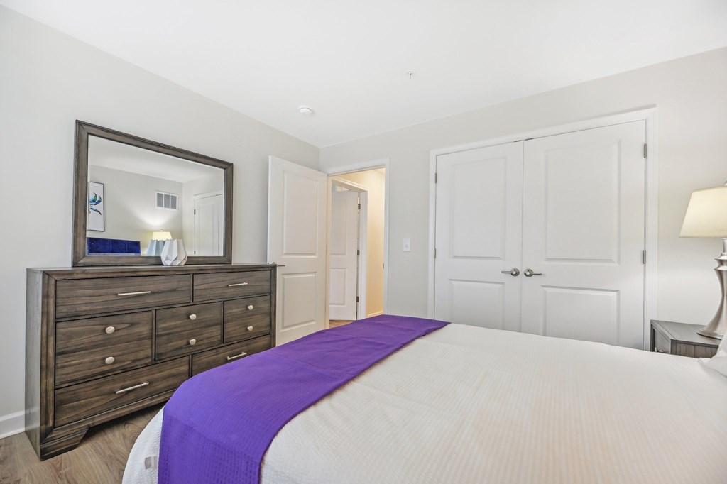 A bedroom with a bed, dresser, and mirror.