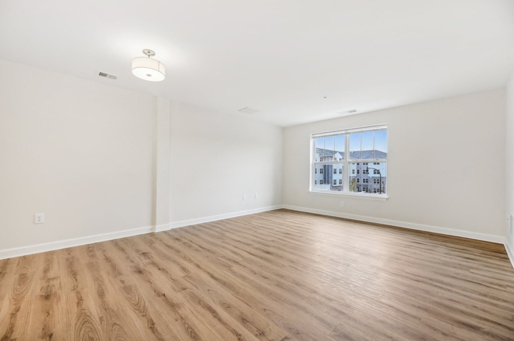 Empty room with wooden floor and a window showing a cityscape outside.