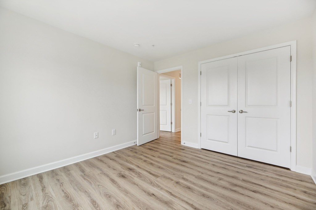 A room with white walls and wooden flooring with two white doors.