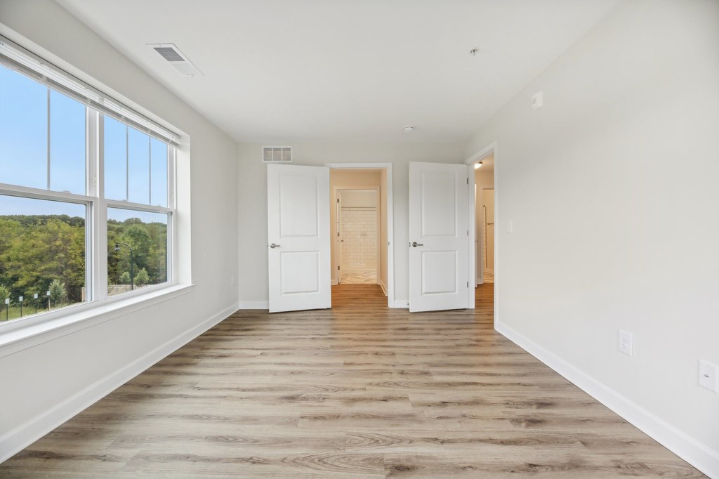 A room with white walls and wooden flooring with two white doors.