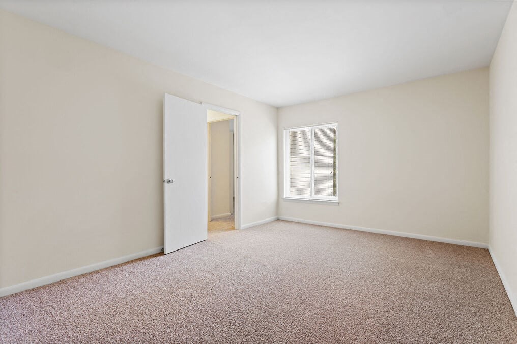 a bedroom with white walls and carpet