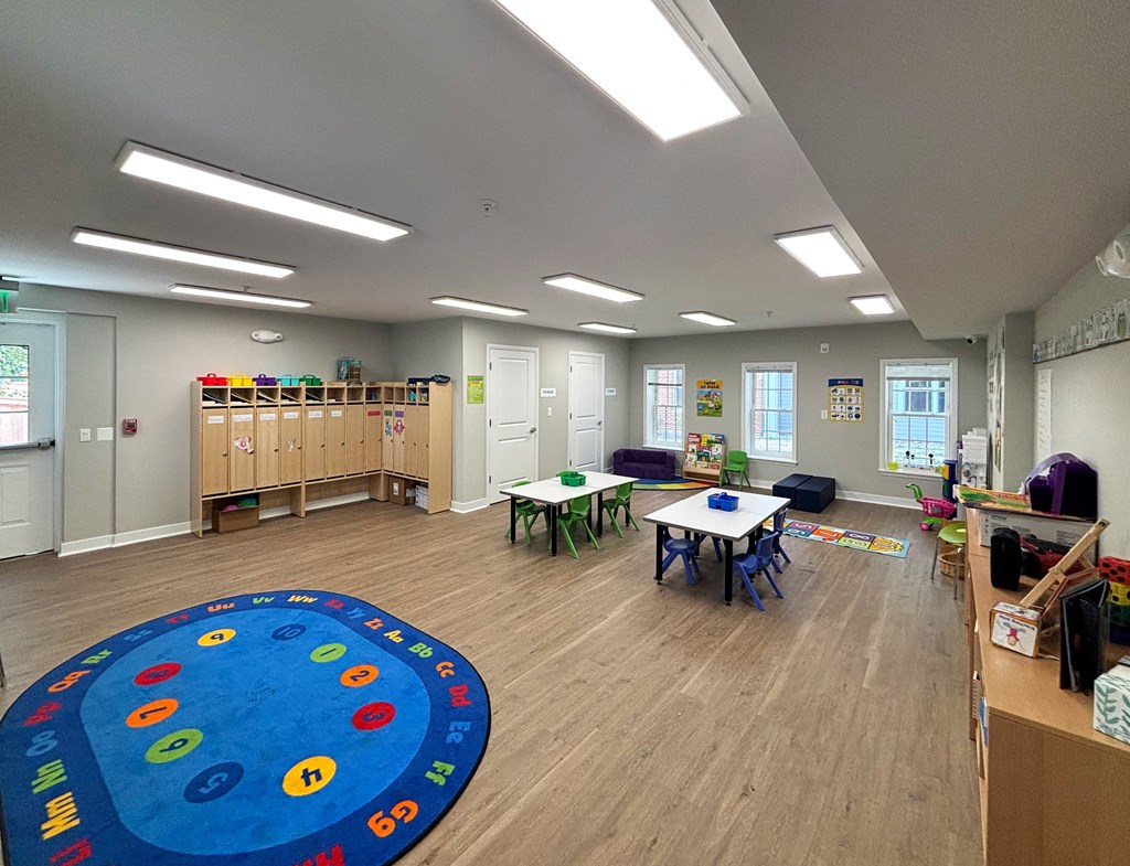 a preschool classroom with tables and chairs and a blue rug in the center