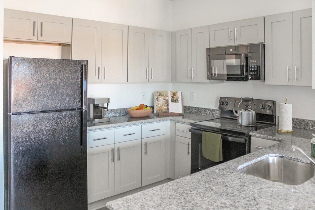 a kitchen with white cabinets and black appliances and granite counter tops
