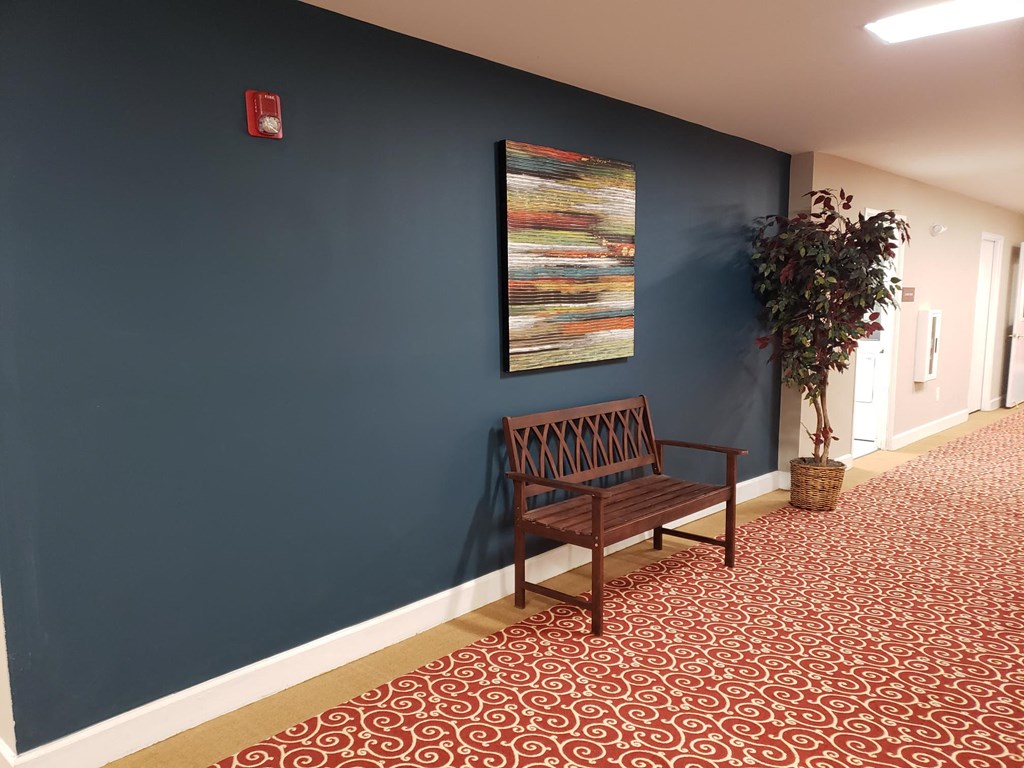 a bench in a hallway with a painting on the wall