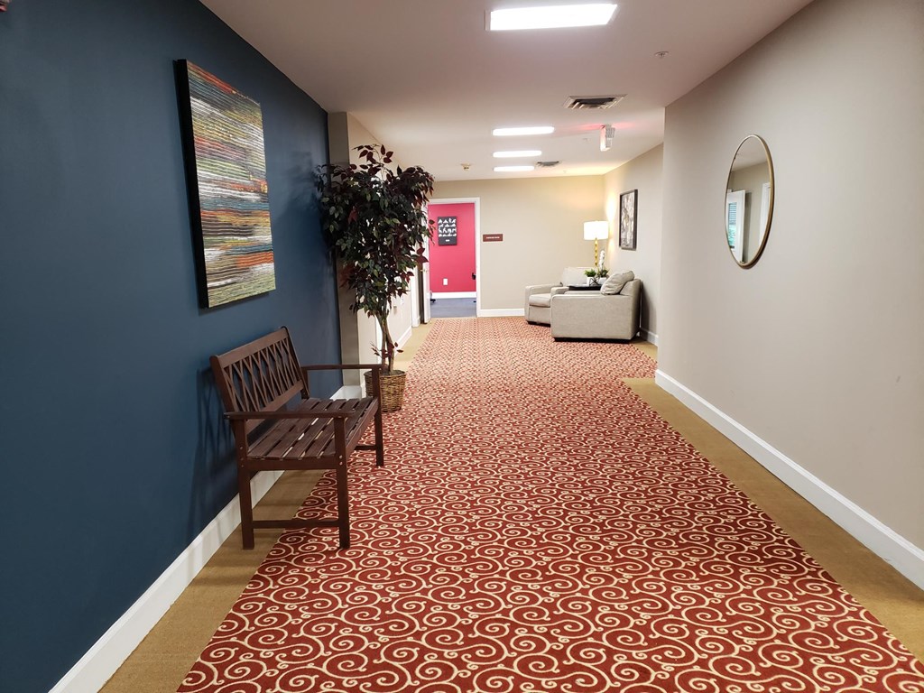 a long corridor with a bench and a pink door
