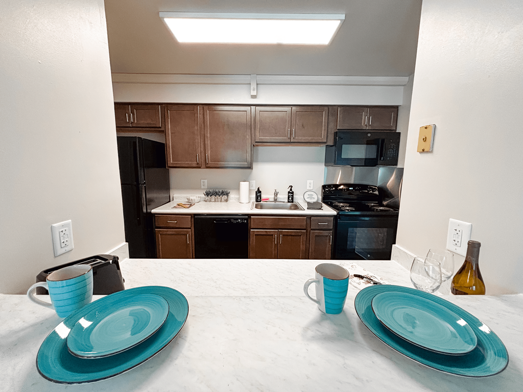 a kitchen with wooden cabinets and a white counter top with blue plates on it