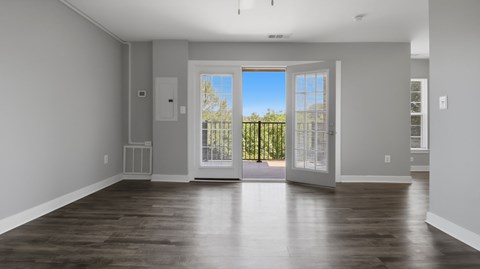 A large empty room with a view of a fence and trees outside.