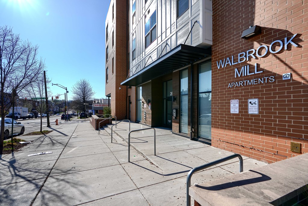 The image shows the exterior of Walbrook Mill Apartments with a clear blue sky in the background.