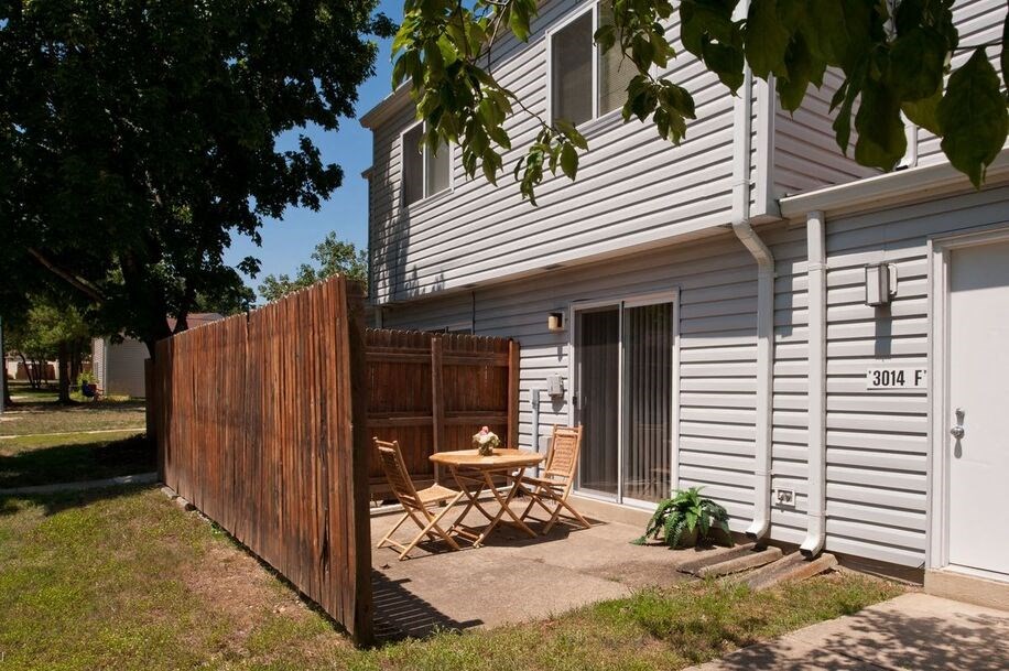a backyard with a wooden fence and a patio with a table and chairs