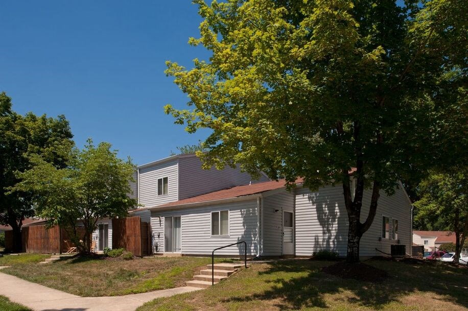 a white house with a gray roof and a tree in front of it