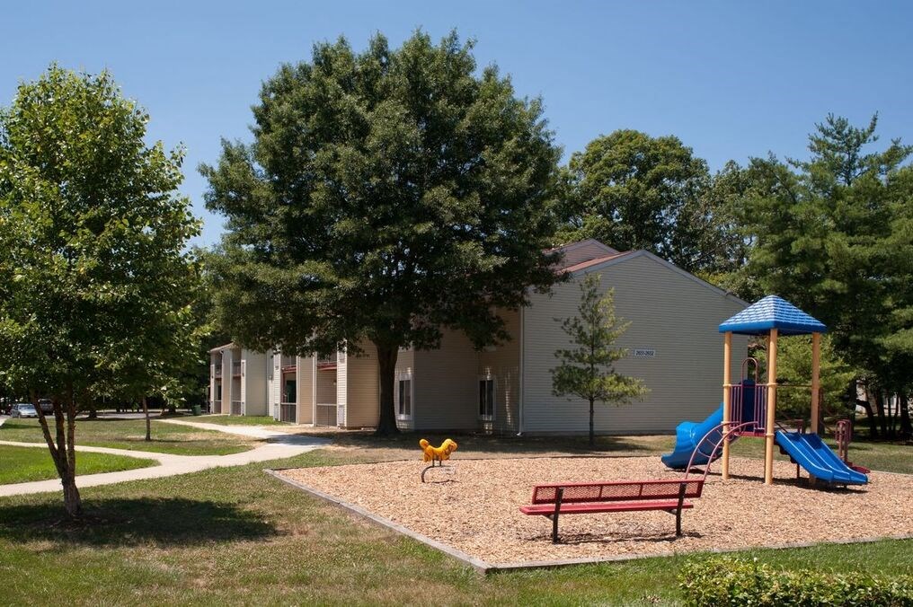 a playground with a picnic table and bench in front of a building