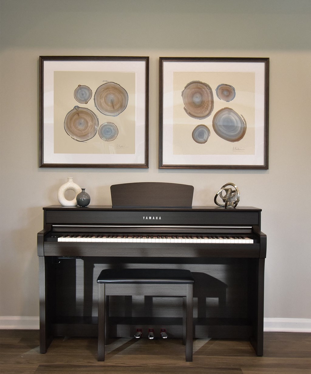 a piano in a living room with two pictures on the wall above it