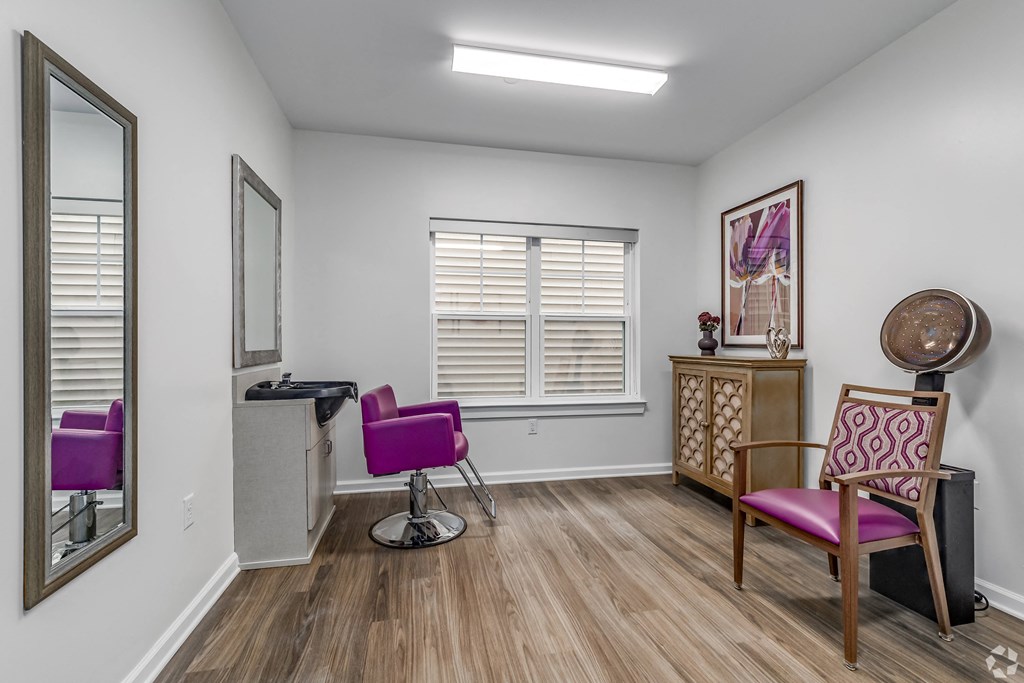 a living room with two purple chairs and a mirror
