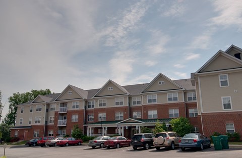 a parking lot in front of an apartment building with cars parked in front
