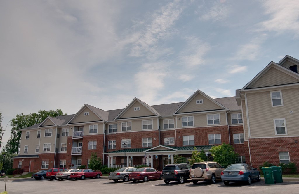 a parking lot in front of an apartment building with cars parked in front