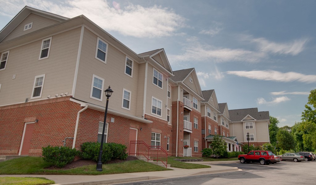 a row of apartment buildings with red cars parked in front