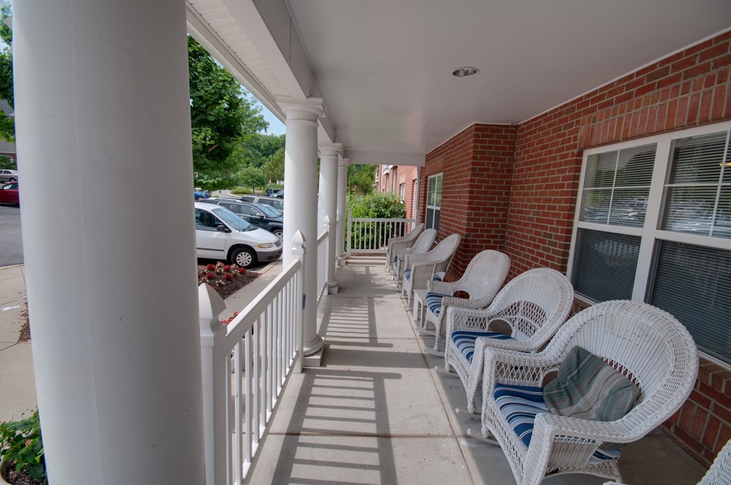a porch with white wicker chairs and a brick building