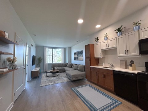 A modern kitchen with a grey sofa and wooden floors.